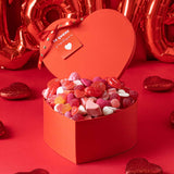 Caja de corazón roja con surtido de chucherías premium.
