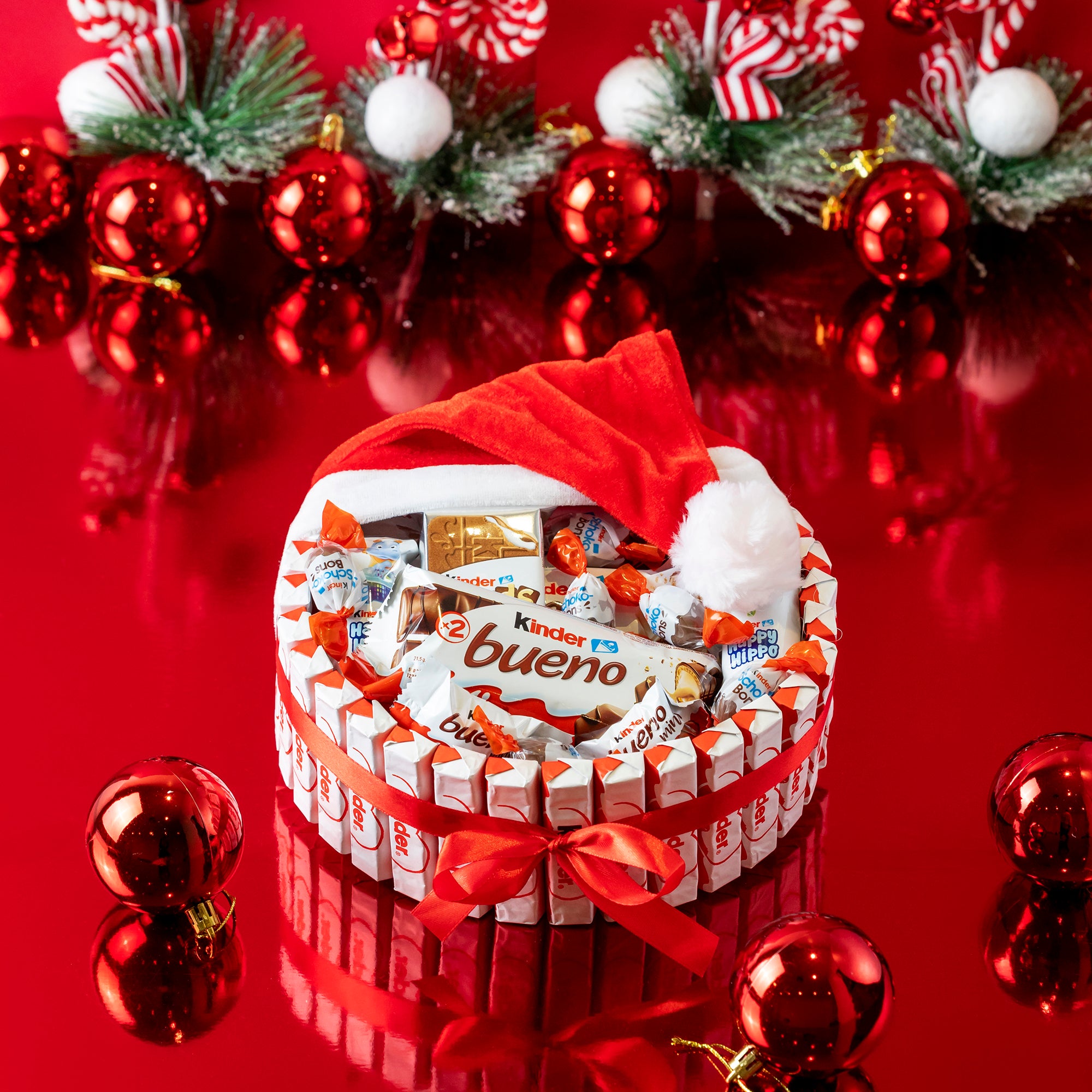 Cesta de chocolates Kinder Bueno con gorro de Papá Noel y surtido de chocolatinas para Navidad.