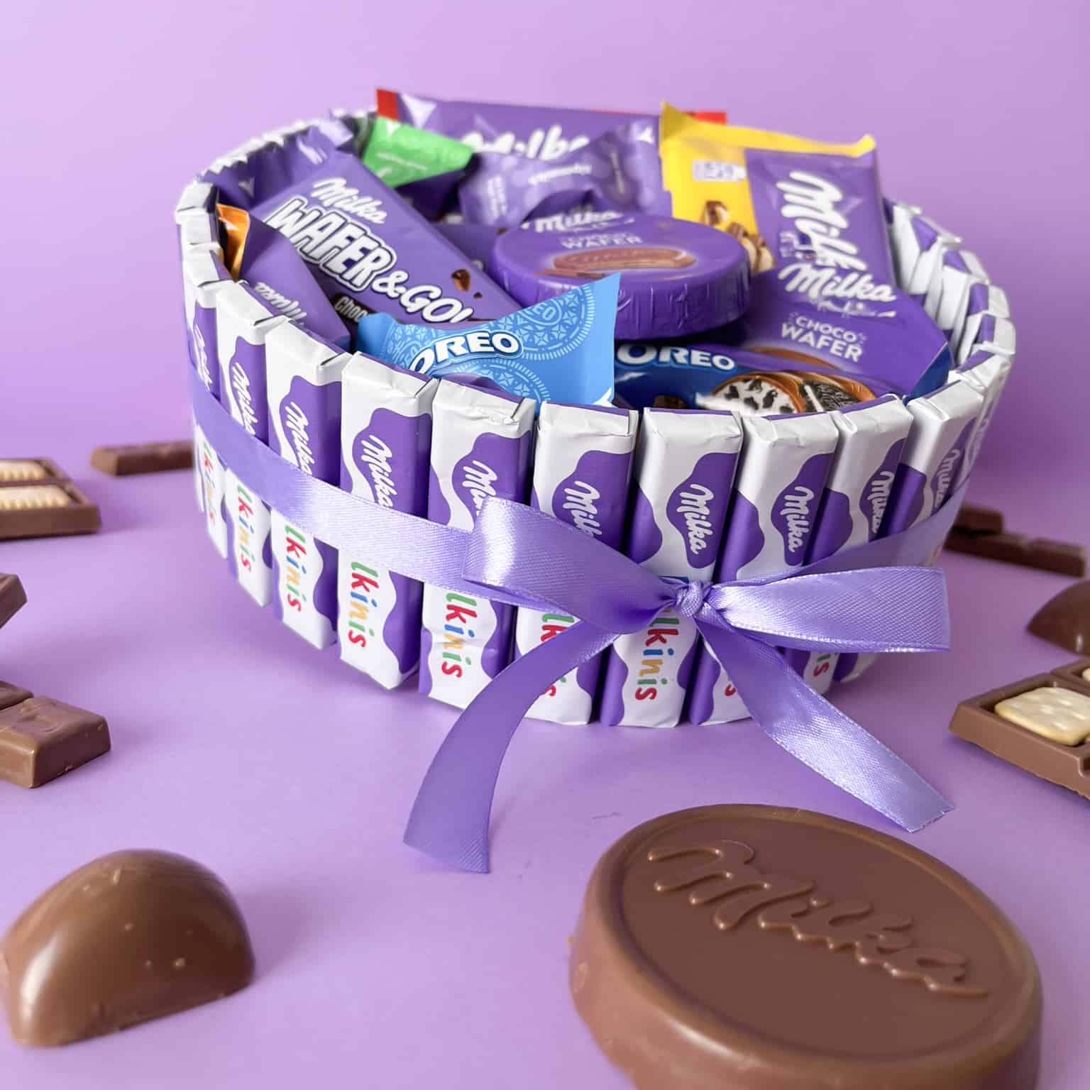 Cesta regalo con chocolates Milka y lazo lila.
