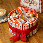 Surtido de chocolatinas Kinder en cesta navideña con decoración roja