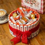 Surtido de chocolatinas Kinder en cesta navideña con decoración roja