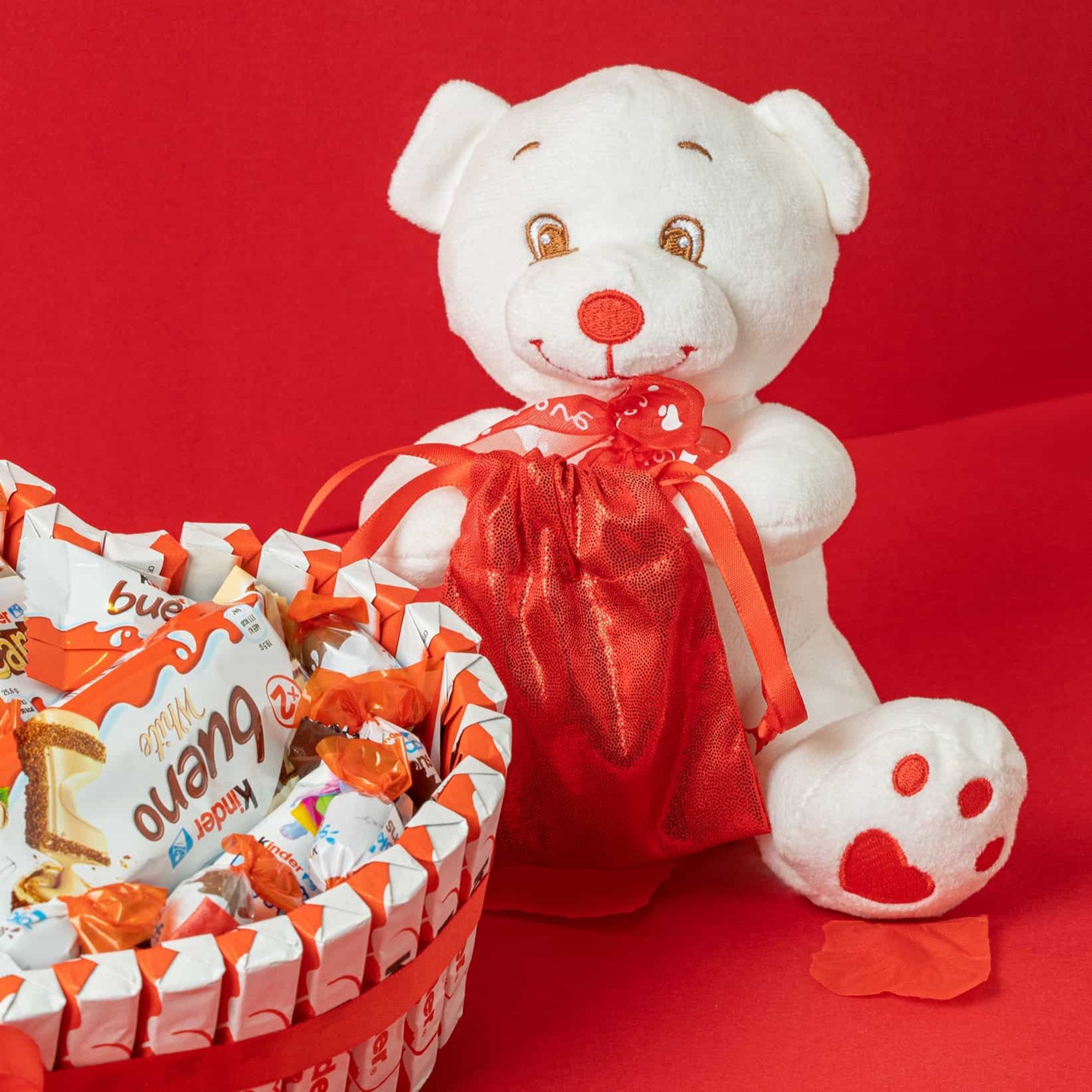 Oso de peluche junto a tarta de chocolates Kinder en forma de corazón.
