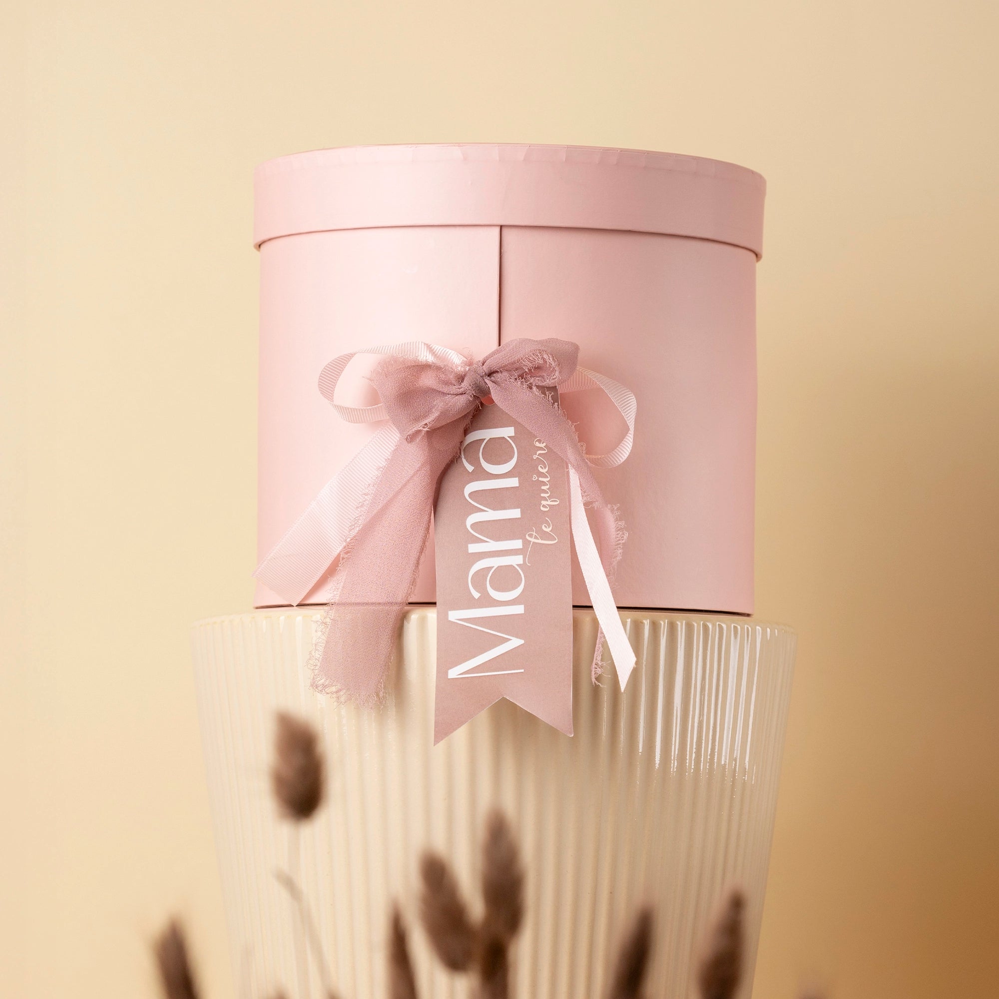 Etiqueta decorativa “Mamá te merece” en caja rosa de regalo para el Día de la Madre

