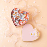 Corazón rosa decorado con lazos y surtido de chocolates Kinder.
